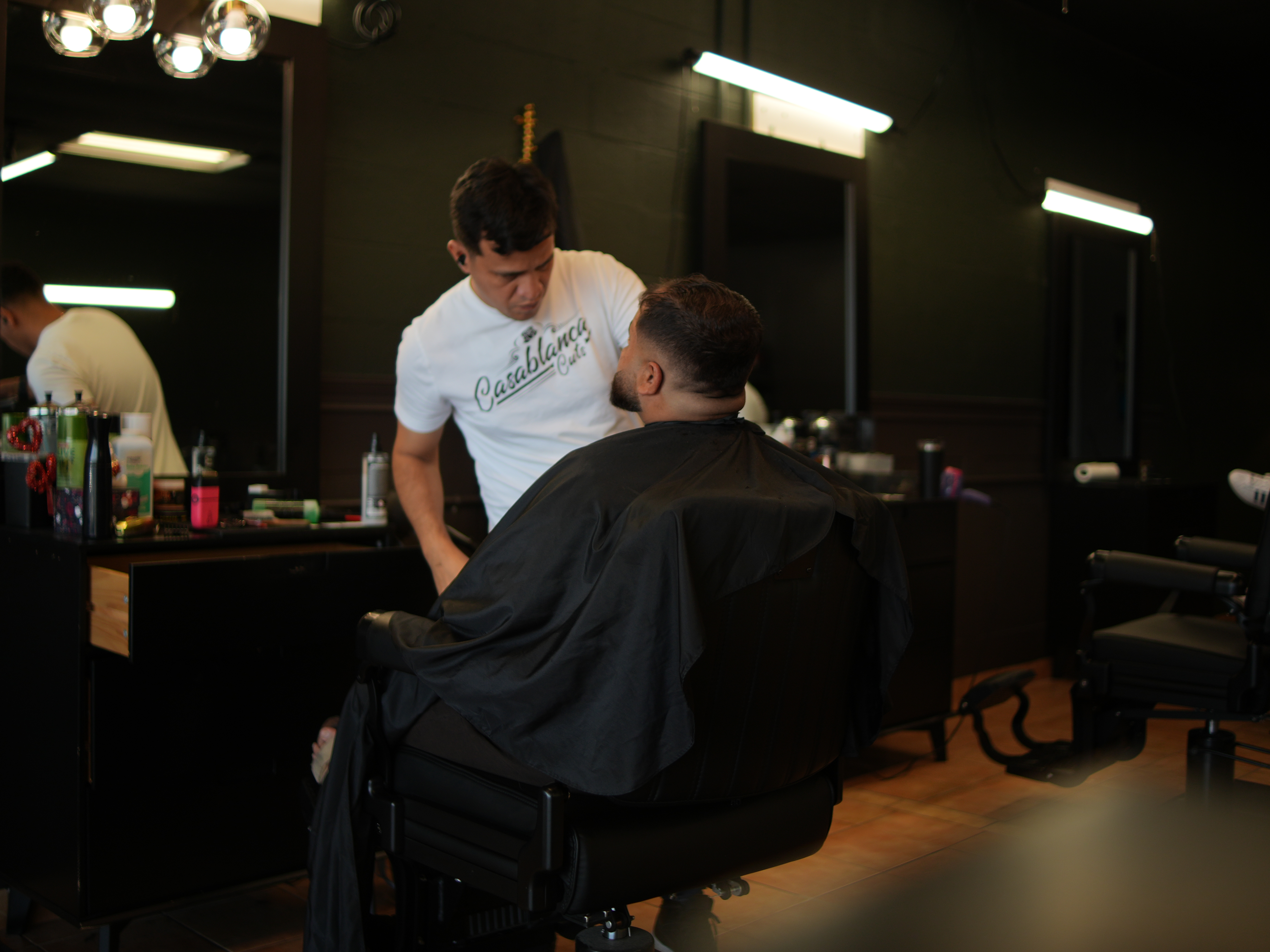 Barber attending to a seated client in the remodeled Hurst shop